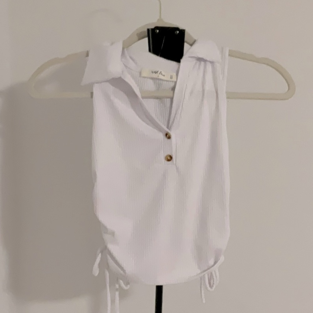 This shirt is white with brown buttons and on the sides there is truffles
